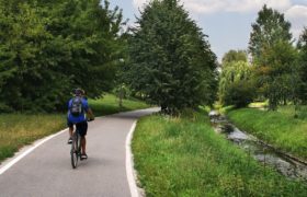 bicyclist riding bike by stream during summer